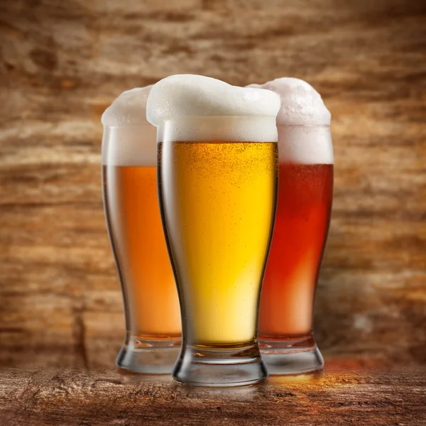 Différentes bières dans des verres sur fond en bois — Photo