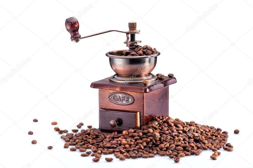 Retro manual coffee mill on roasted coffee beans isolated