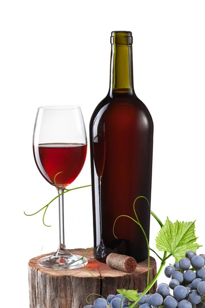 Copo de vinho tinto, garrafa e uva no toco isolado no branco — Fotografia de Stock