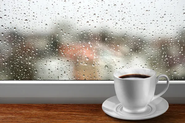 Xícara de café contra janela com vista dia chuvoso — Fotografia de Stock
