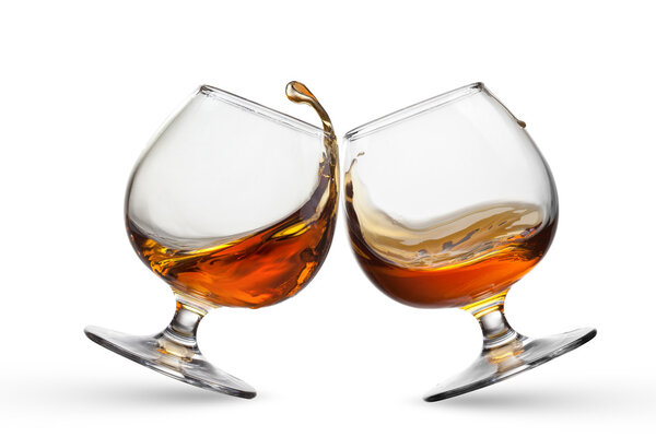 Splash of cognac in two glasses isolated on white background