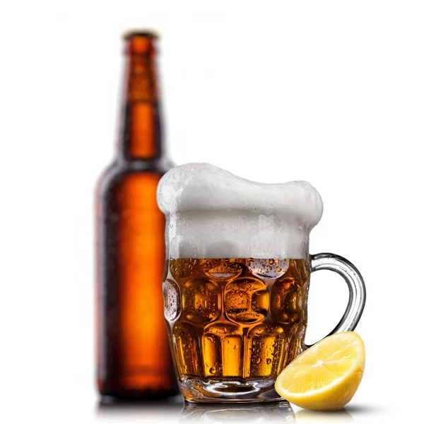 Beer in glass with water drops and lemon against bottle isolated — Stock Photo, Image