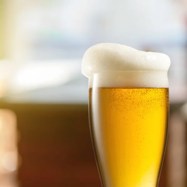 Glass of light beer in pub — Stock Photo, Image