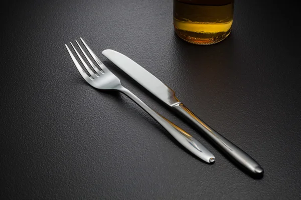 Botella de cerveza, cuchillo y tenedor en negro —  Fotos de Stock