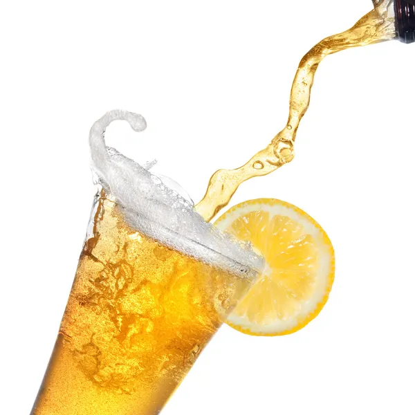 Birra versata da bottiglia in bicchiere con limone isolato su bianco — Foto Stock