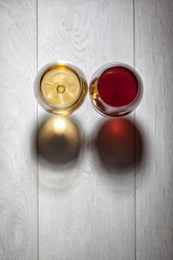 Glasses of red and white wine on wooden table clipart