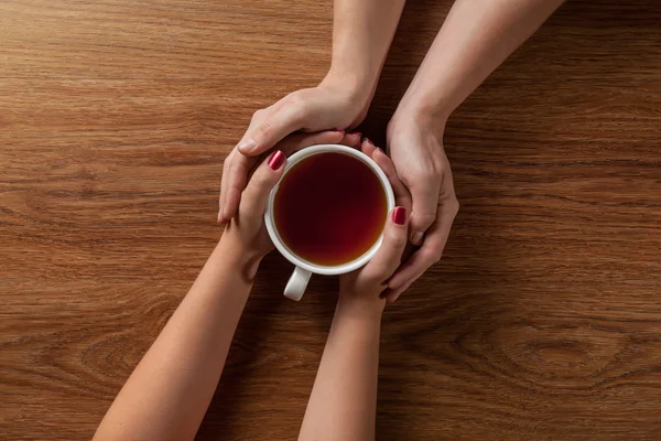 Woman holding hot cup of tea with cookies — Stock Photo, Image