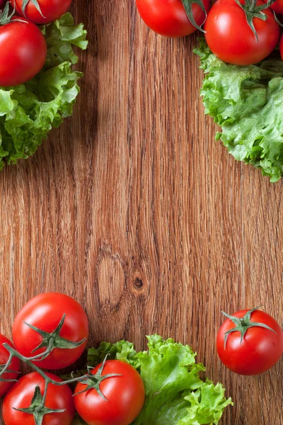 Red tomatoes with green salad on wood — Stock Photo, Image