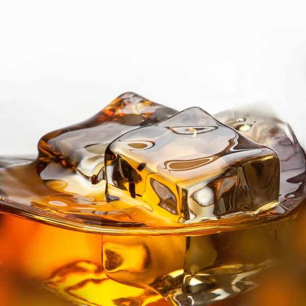 Eclaboussure de whisky avec glace dans un verre isolé sur fond blanc — Photo