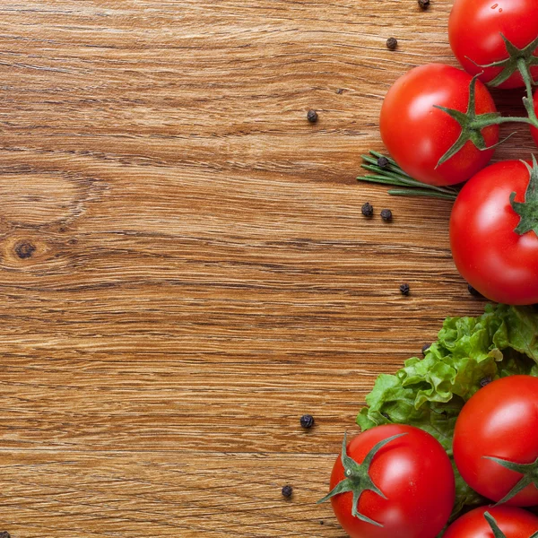 Tomates vermelhos com salada verde em madeira — Fotografia de Stock