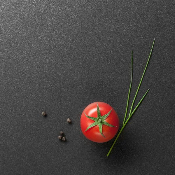 Pomodoro rosso con cipolla verde su nero — Foto Stock