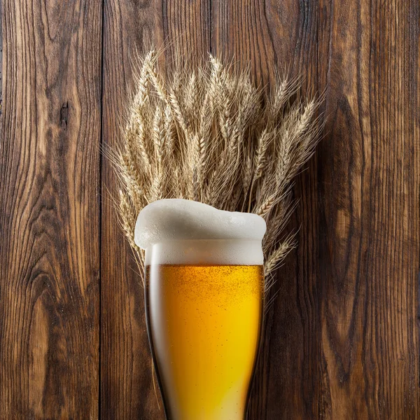 Glass of beer with wheat on wood — Stock Photo, Image