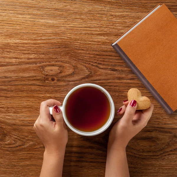 Woman holding cup of tea with cookie — Stock Photo, Image