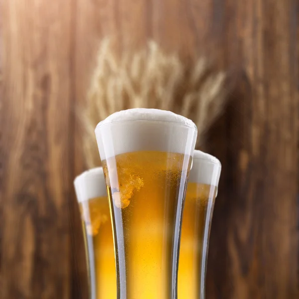 Bicchiere di birra con grano su legno — Foto Stock