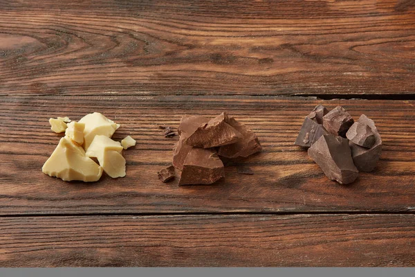 从上面的一组白色 牛奶和黑巧克力碎成块 排成一排放在木制桌子上 — 图库照片