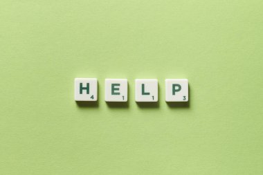 Yeşil arka planda Scrabble bloklarından oluşan yardım kelimesi. Yardım ve acil durum kavramı.