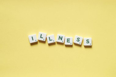 Sarı arka planda dağınık Scrabble bloklarından oluşan hastalıklı bir kelime. Tehlikeli hastalıklar ve fiziksel sağlık farkındalığı.