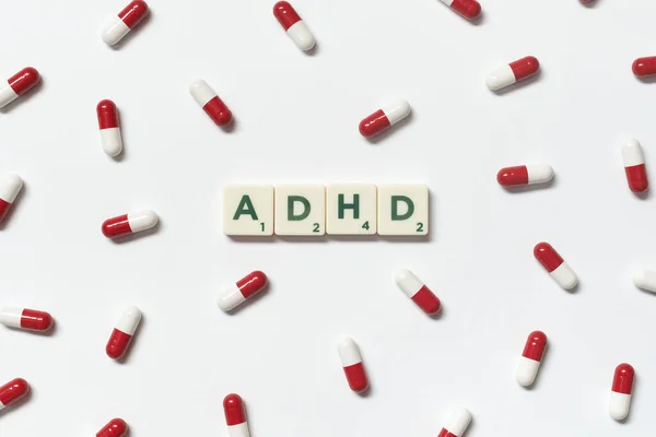 白い背景の上に広がるスクラブルブロックと医薬品の丸薬で形成されたAdhdの単語 注意欠陥多動性障害と精神衛生意識 — ストック写真