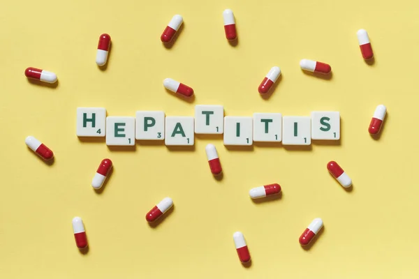 Hepatit Kelimesi Scrabble Blokları Sarı Arka Plana Saçılmış Ilaç Haplarından — Stok fotoğraf