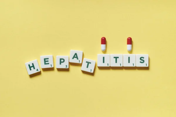 Hepatit Kelimesi Scrabble Fayanslarından Oluşur Sarı Arka Fonda Iki Ilaç — Stok fotoğraf