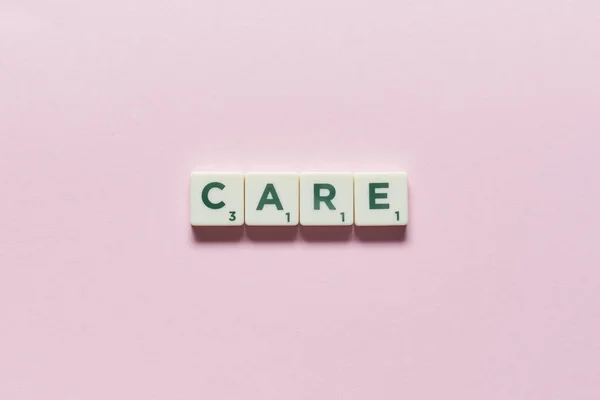 Заботливое Слово Сформированное Скраббла Блоков Розовом Фоне Концепция Медицинского Страхования — стоковое фото