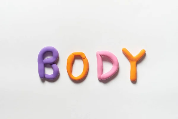 Body word formed of colorful plasticine on white background.