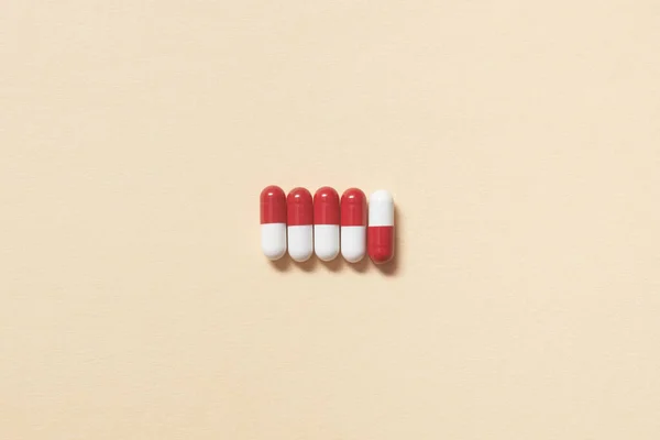 红色和白色的药丸整齐地铺在米色的背景上 保健和药物辅助治疗 — 图库照片