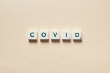 Bej arkaplanda Scrabble fayanslarından oluşan gizli bir kelime. Coronavirus enfeksiyonu ve tıbbi tedavi kavramı.