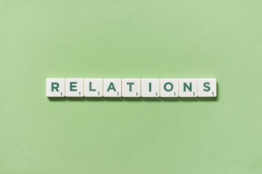 Yeşil arkaplanda Scrabble bloklarından oluşan ilişkiler sözcüğü, kopyalama alanı ile natürmort yaşam.