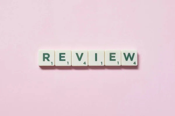 Review Woord Gevormd Van Scrabble Blokken Roze Achtergrond Stilleven Met — Stockfoto