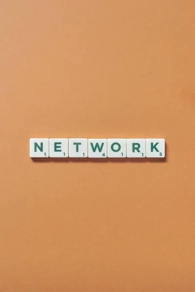 Network word formed of scrabble tiles on brown background, still life with copy space.