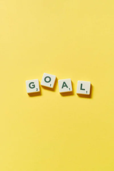 Goal word formed of scrabble tiles on yellow background, still life with copy space.