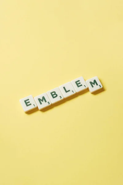 Emblem Word Formed Scrabble Tiles Yellow Background Still Life Copy — Stockfoto