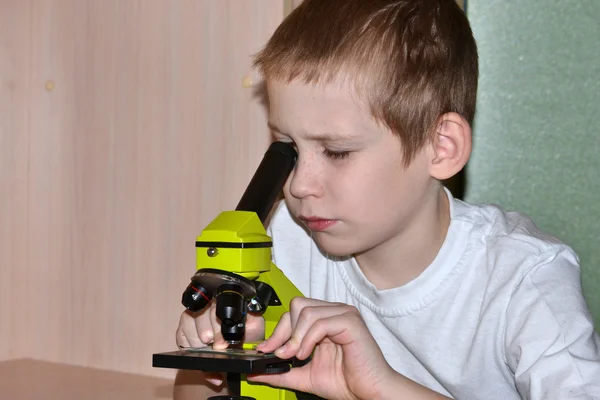 Chlapec se podívá do mikroskopu. — Stock fotografie