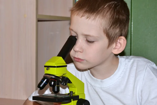Pojken tittar i ett mikroskop — Stockfoto