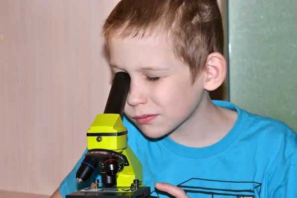 The boy looks in a microscope — Stock Photo, Image