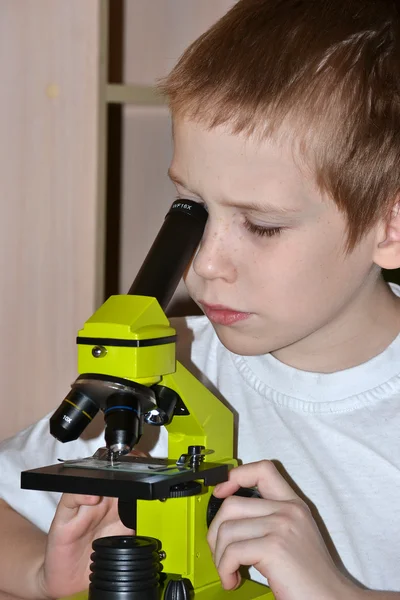 Chlapec se podívá do mikroskopu. — Stock fotografie