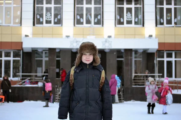 The boy costs against school in the winter — Stock Photo, Image