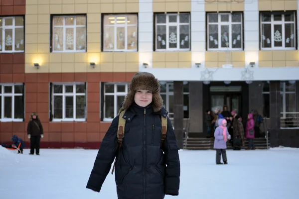 The boy costs against school in the winter — Stock Photo, Image