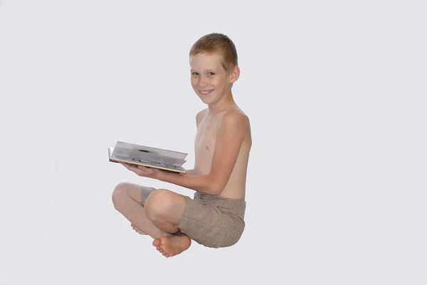 Pojken håller boken och leenden — Stockfoto