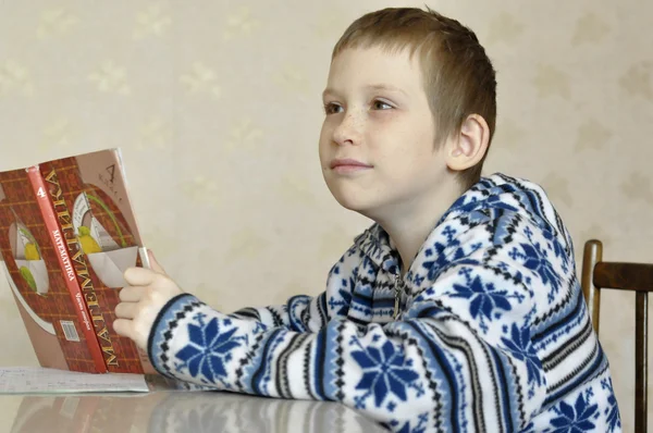 10-årige pojken sitter med läroboken, göra läxor. — Stockfoto