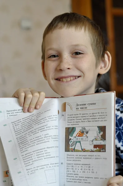 10-летний мальчик сидит с учебником, делает домашнюю работу . — стоковое фото