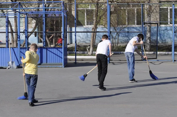 Les adolescents balayent la cour avec des balayeuses pendant un travail communautaire d — Photo