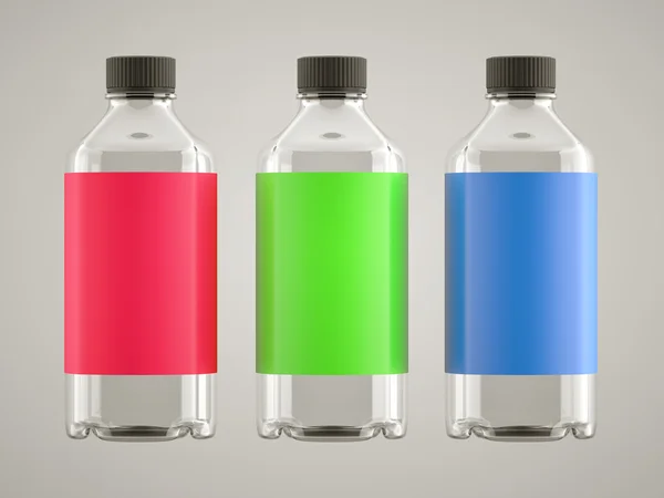 Три бутылки с яркими наклейками на сером — стоковое фото