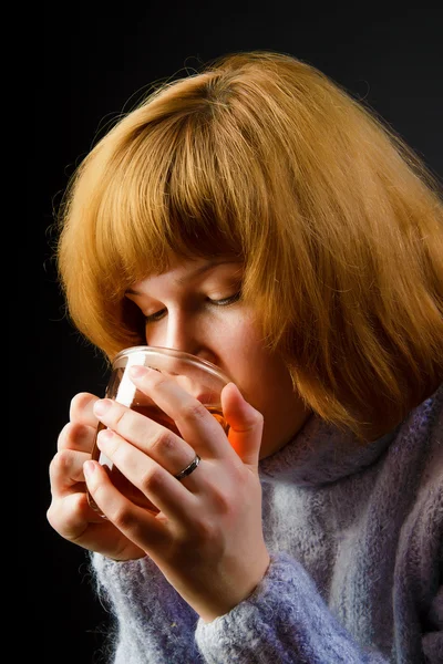 Girl in a sweater on a black background drinking tea — Stock Photo, Image