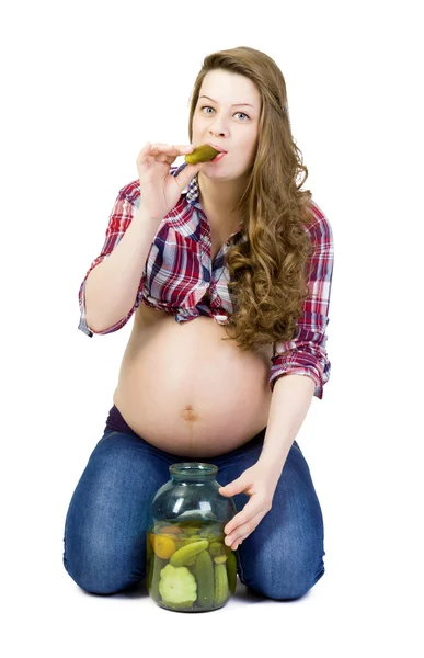 Une jeune femme enceinte sur fond blanc mange du concombre mariné — Photo