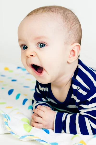 Niedliches Baby in gestreifter Kleidung auf einer Decke liegend — Stockfoto