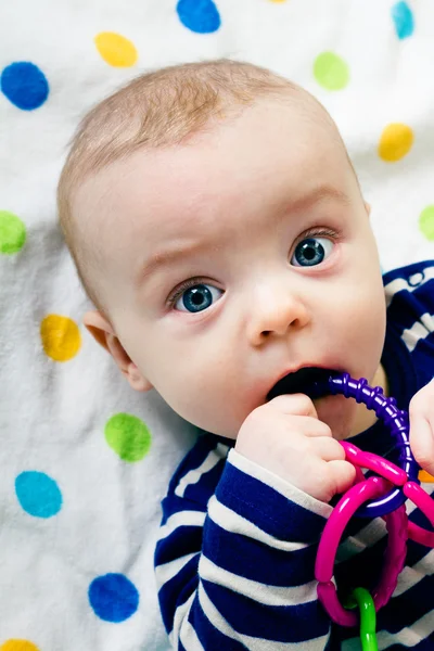 Niedliches Baby in gestreifter Kleidung auf einer Decke liegend — Stockfoto