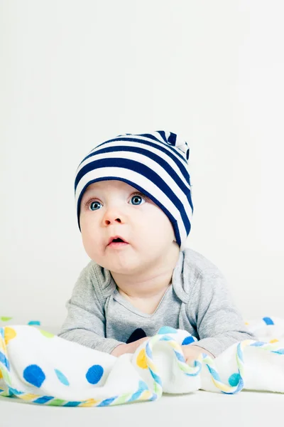 Cute baby in striped hat lying down on a blanket — Stock Photo, Image