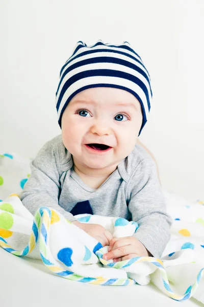 Cute baby in striped hat lying down on a blanket — Stock Photo, Image